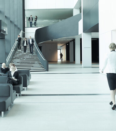 Modern business people walking in glass hall of office building