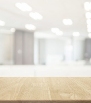 Wood table top and blurred bokeh office interior space background - can used for display or montage your products.