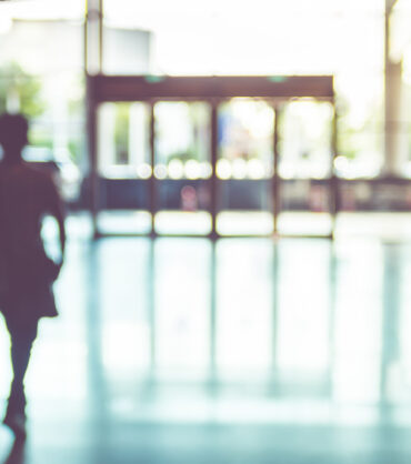 Blur background,silhouette of Business man walking at corridor in convention hall with sun light at door.