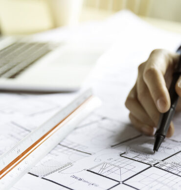 Close up woman hand working of Architect sketching project on blueprint at site construction work. Concept of architect, engineer in the office desk construction project banner