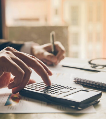 Close up hands businessman doing finances with using calculator and writing note in office