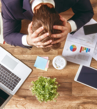businessman in panic. a young man sits at his Desk and holds his hands on his head.