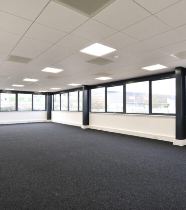 view of a new empty office area with windows on two sides and carpeted