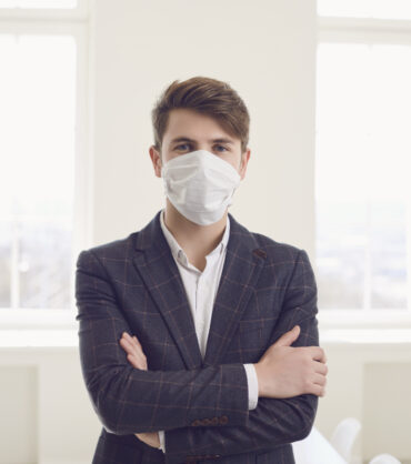 Danger of infection of the virus coronavirus infection. Businessman in medical mask at office on window background.