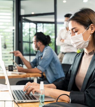 Asian young businesswoman wearing mask working on computer in office