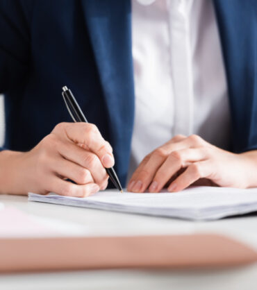 cropped view of team leader signing documents on desk