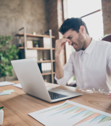 Profile side photo of exhausted middle eastern entrepreneur have lots work on computer, touch his nose hold glasses feel burnout sit desk in loft wearing white shirt