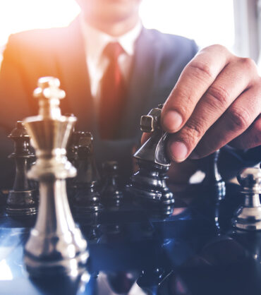 Detail of a hand making the first move in a chess game, moving the pawn one field forward. Selective focus