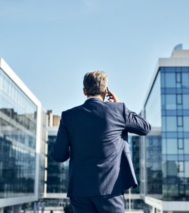 portrait of a senior businessman in front of corporate buildings