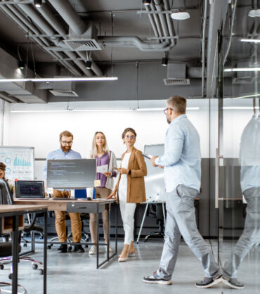 Interior view on the modern office room with diverse people working on the computers indoors