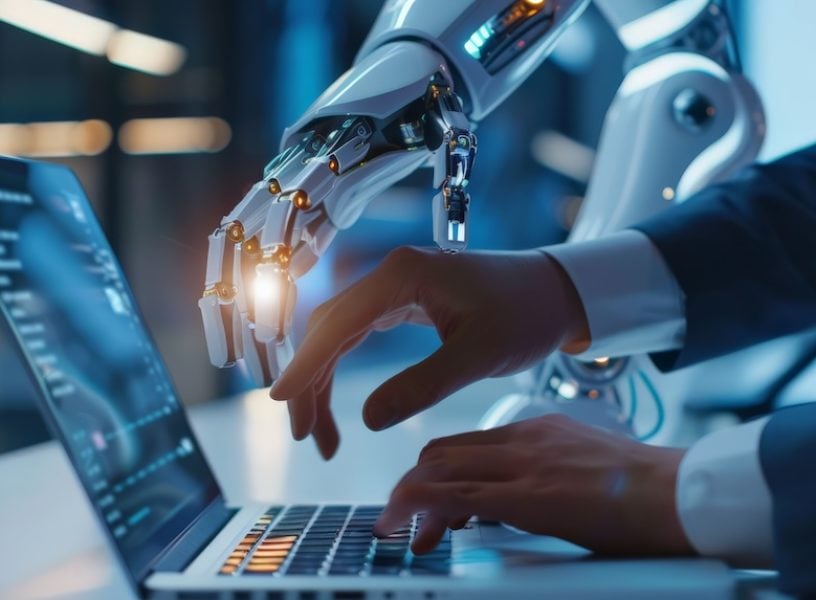 Human and robotic hand working together on a laptop. Collaboration between AI and humans Human and robotic hand working together on a laptop. Collaboration between AI and humans.